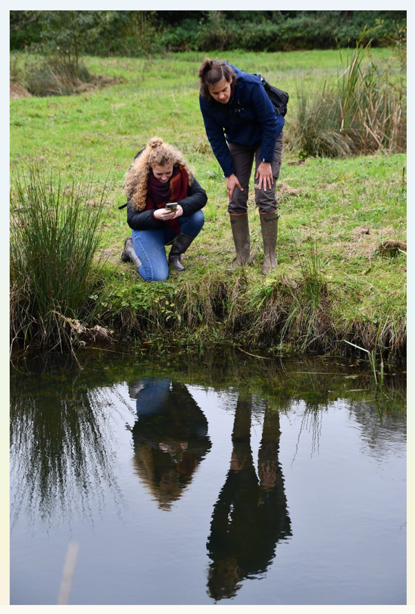 Photo de deux personnes penchées au-dessus d'un point d'eau avec un smartphone